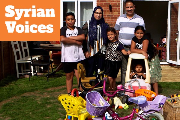 family stand together in backyard, orange box in top left corner