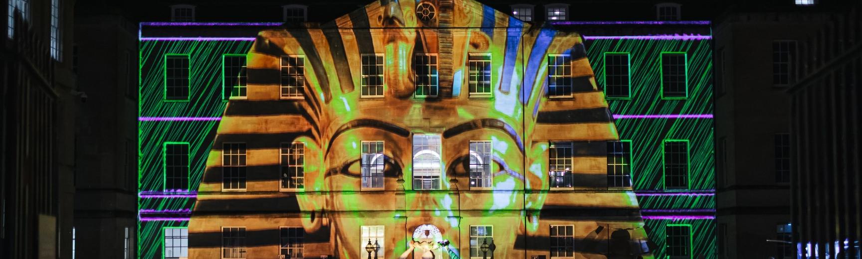 Front of TORCH building with the head of a golden Egyptian sarcophagus projected onto it