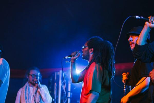 Musicians singing into microphones in a darkened room