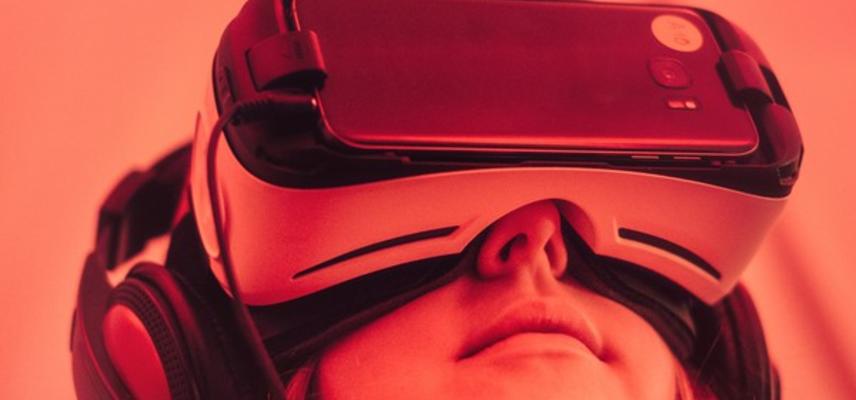 Pink tinted photo of a young girl wearing a VR headset and big headphones