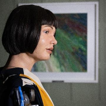 Aida lucy seal AiDa robot in short black hair in front of a painting