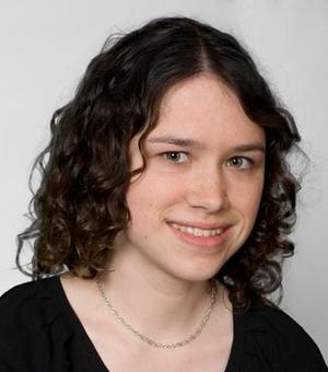 Sian Pooley, with curly, short hair smiles at the camera